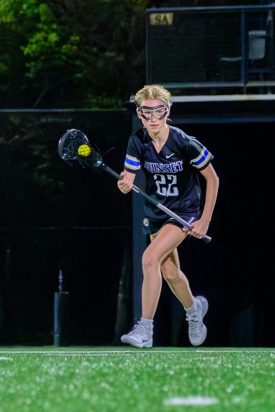 Sunset player wearing number 22 running with the ball in a lacrosse stick.