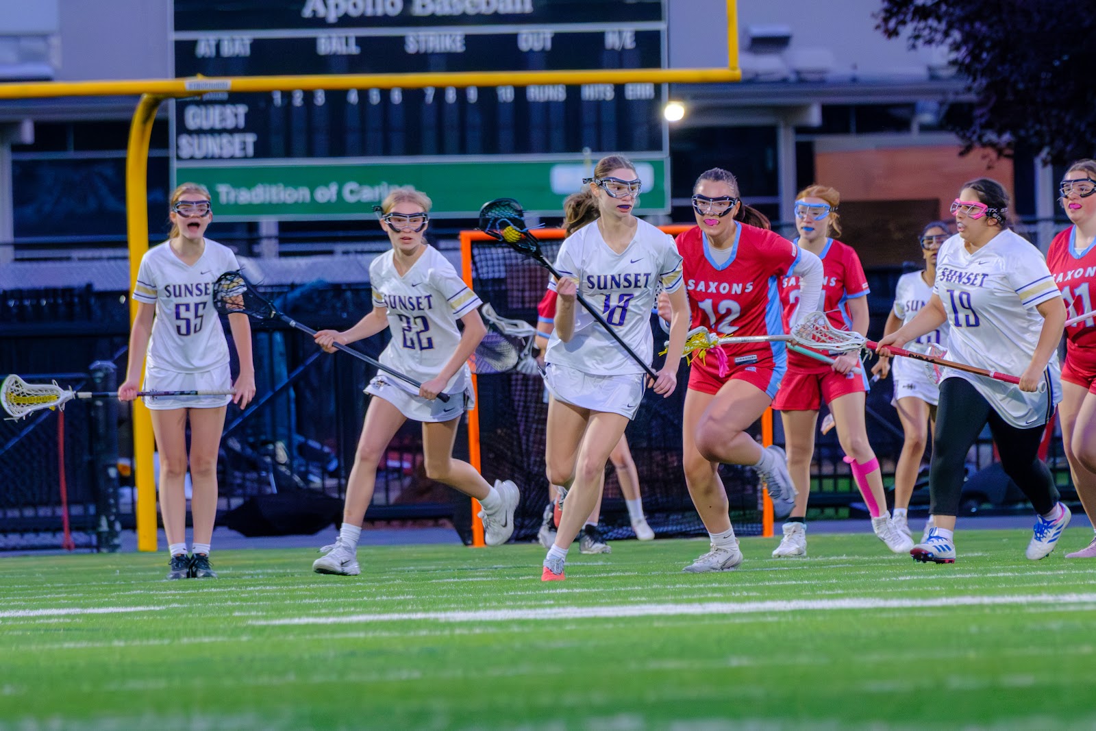 Sunset players in white uniforms moving together during a lacrosse game.